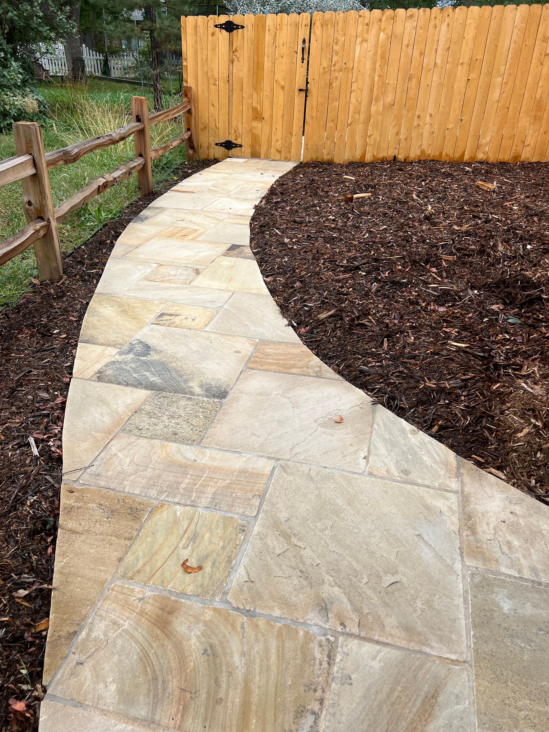 A stone walkway with a wooden fence in the background.