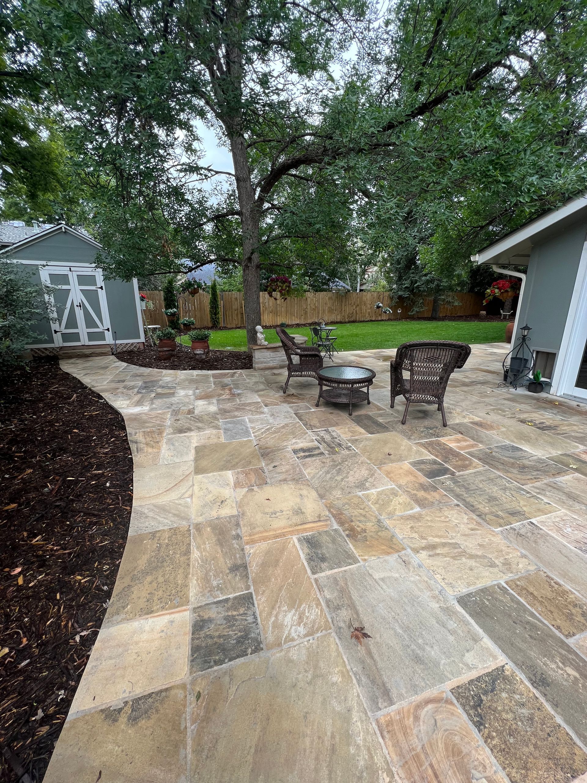 A patio with a fire pit and chairs in the backyard of a house.