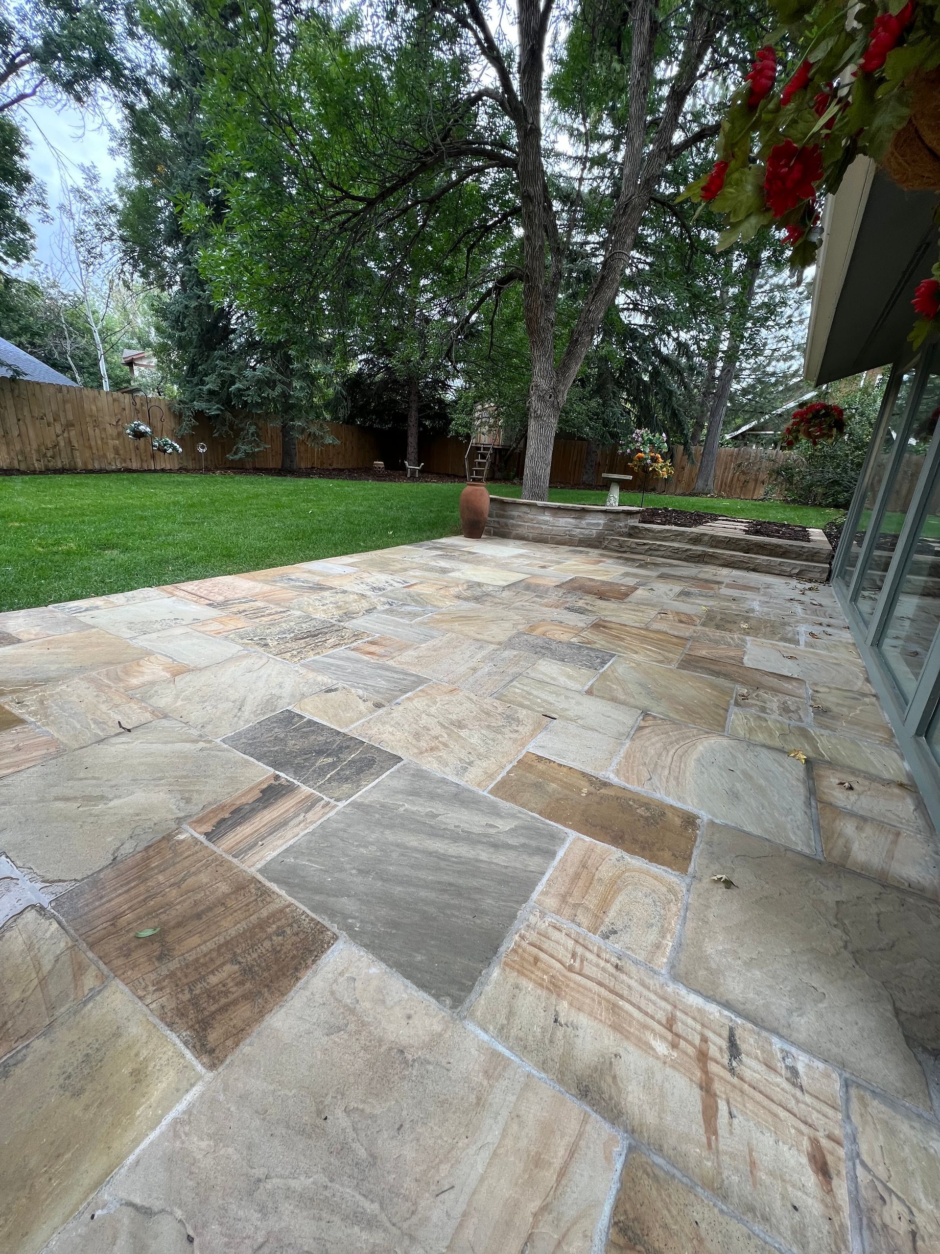 A patio with a lot of tiles and trees in the background.