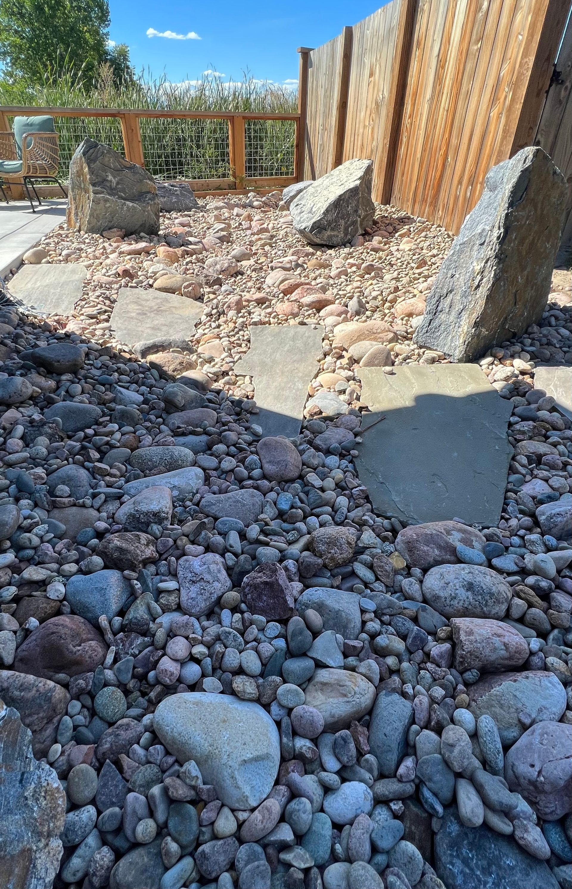A pile of rocks in a yard with a wooden fence in the background.