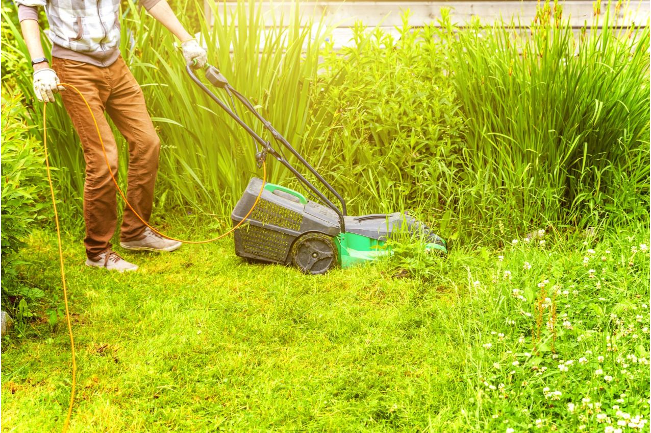 A man is cutting the grass with a lawn mower.