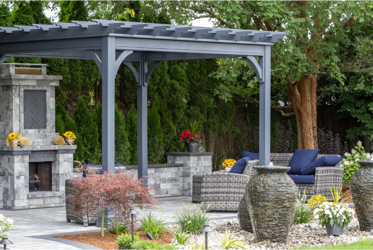A patio with a pergola , chairs , and a fireplace.