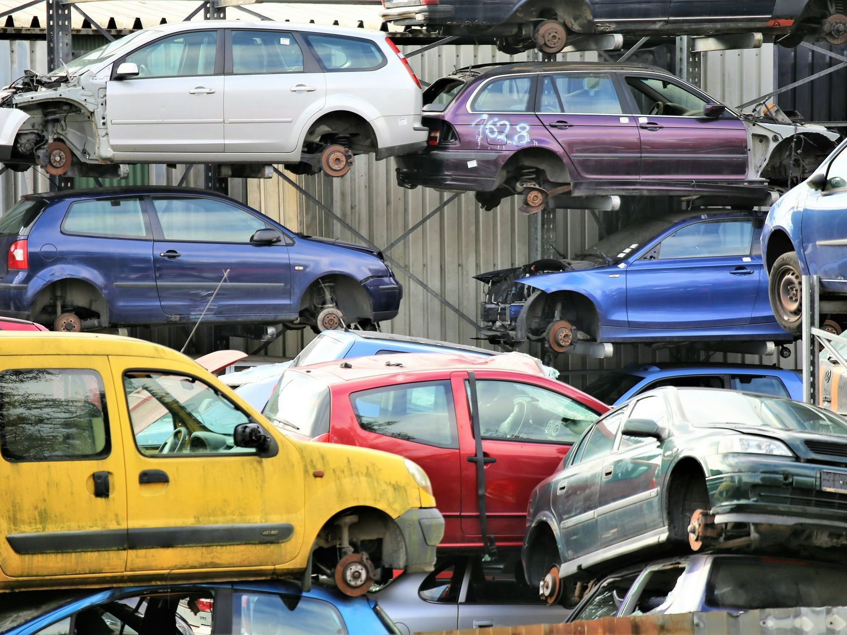 A bunch of cars are stacked on top of each other in a junkyard.