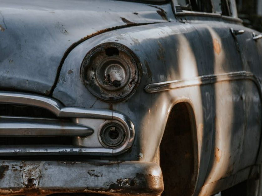 A close up of the front of an old rusty car.