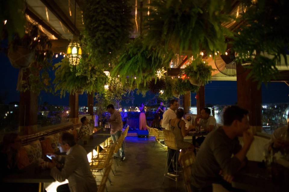 Nighttime scene at Upper Buena Vista in Miami with outdoor bars, string lights, and a lively crowd