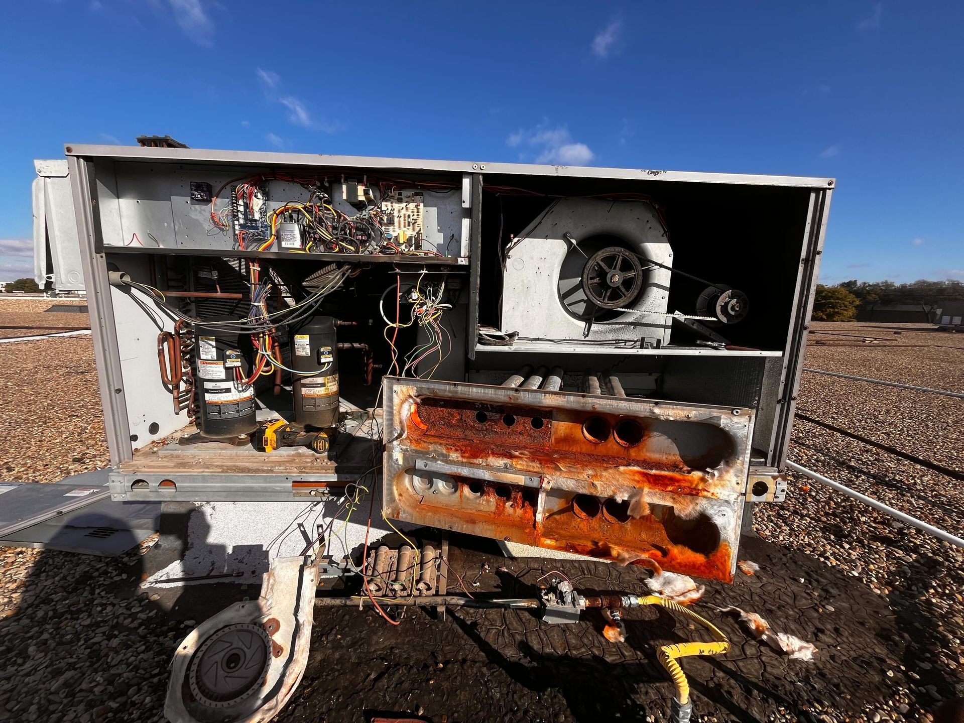 A rusty air conditioner is sitting on the ground in a field.