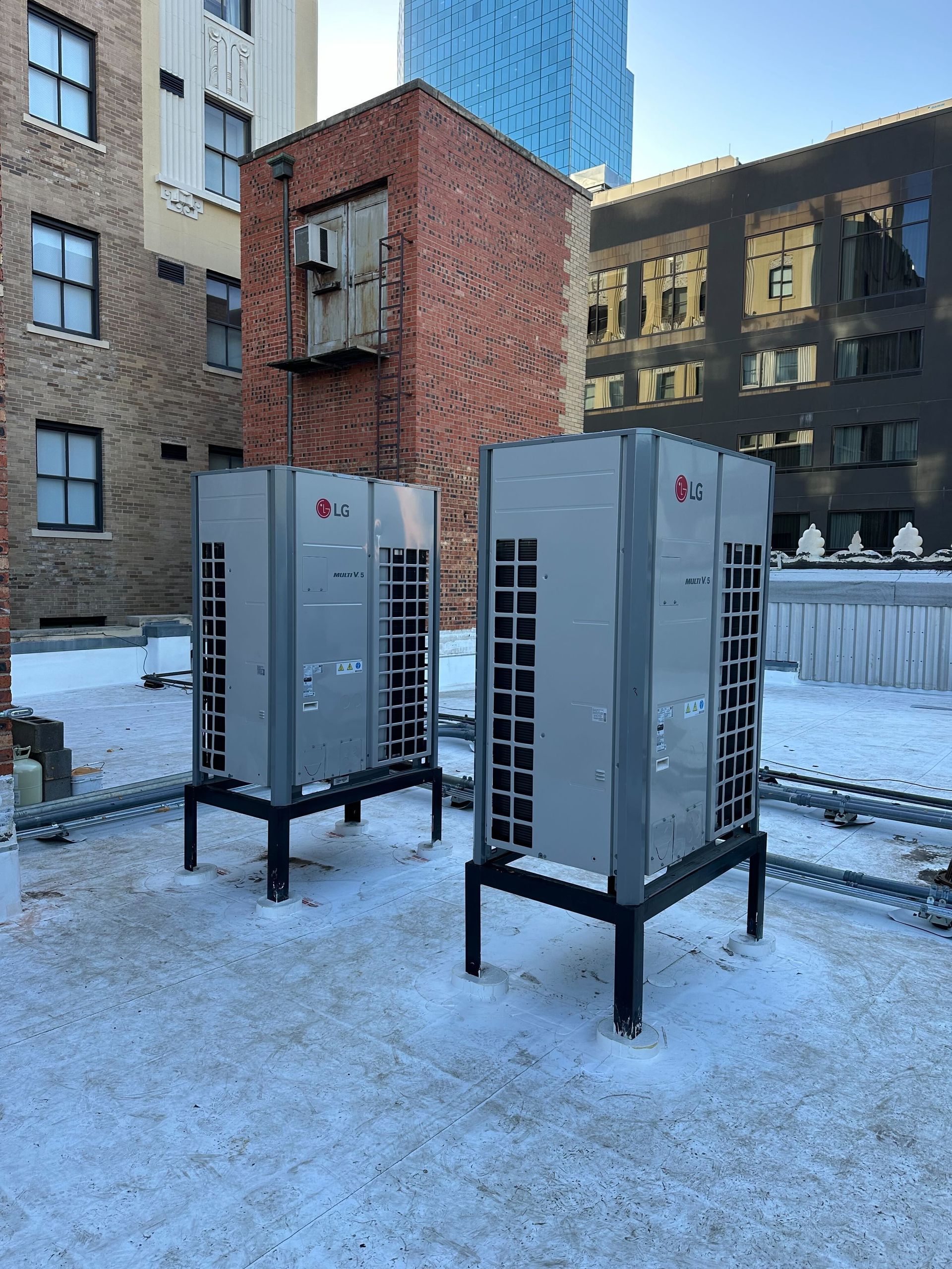 Two air conditioners are sitting on top of a snow covered roof.