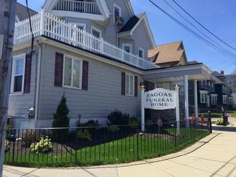 The front door of a house with a porch and plants in front of it.