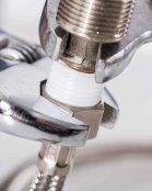 A close up of a wrench on a faucet.