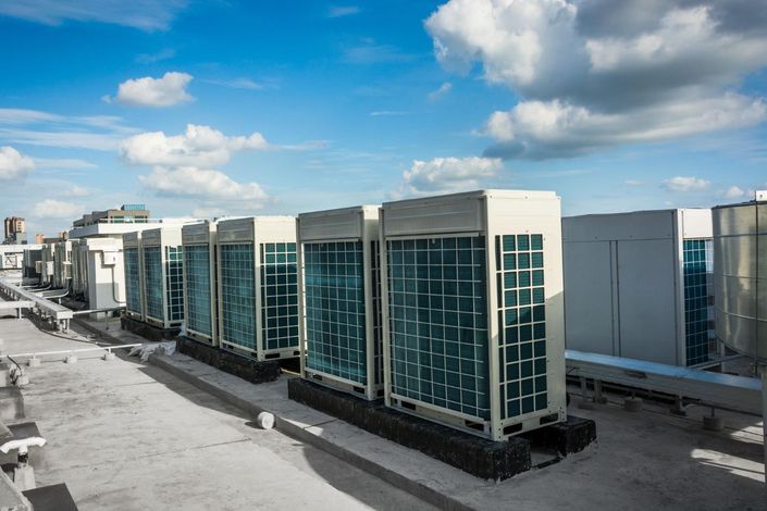 Rooftop view of large industrial HVAC units with glass panels under a blue sky.