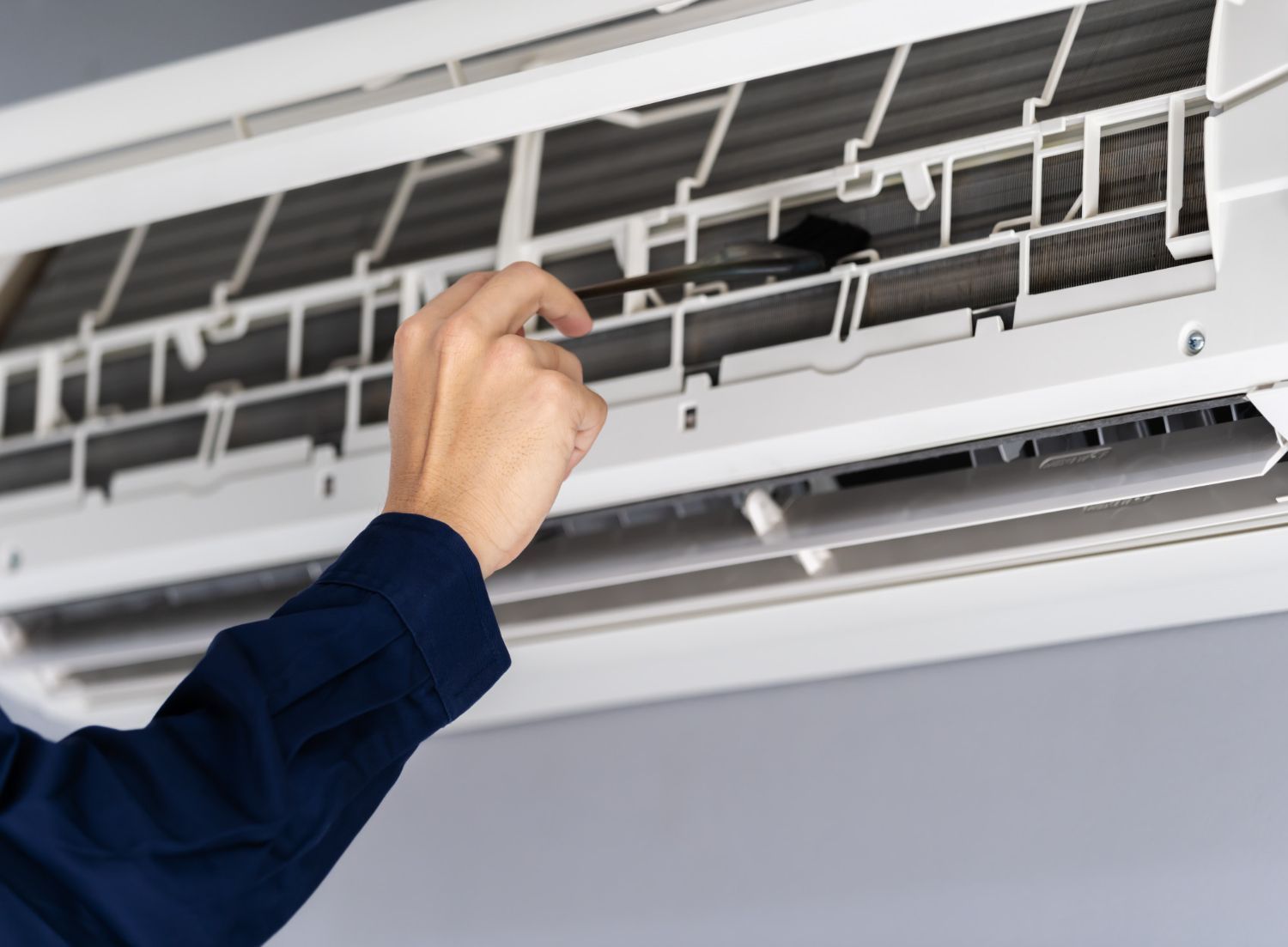 Hand adjusting the filter of a wall-mounted air conditioner with the front panel open