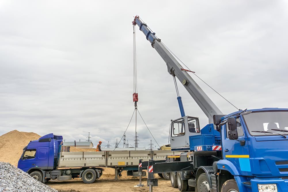 A Crane is Lifting a Concrete Slab From a Truck at a Construction Site — Alexander Crane Tippers in Bungendore, NSW
