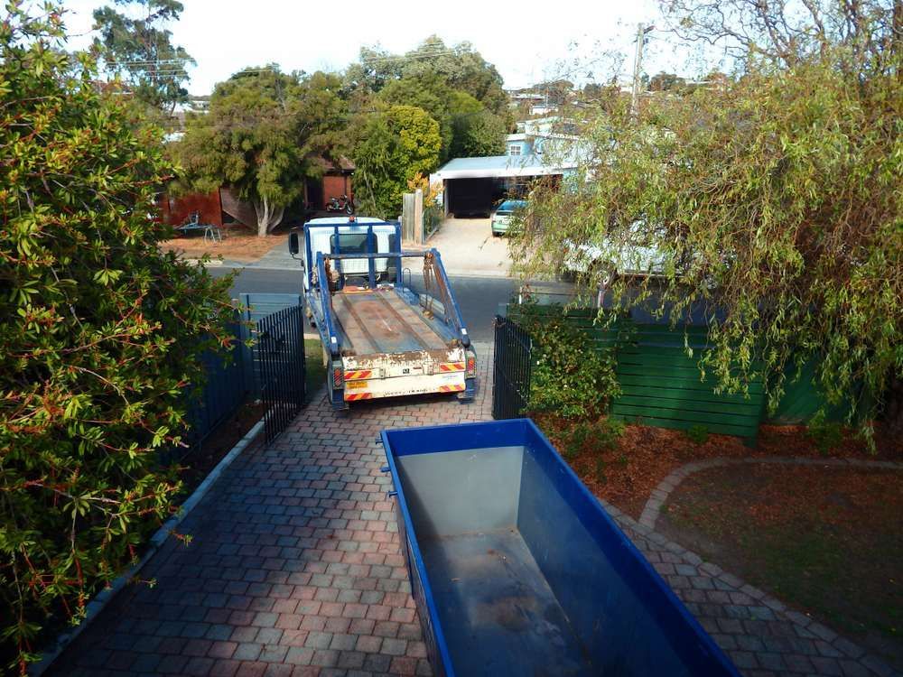 A Blue Dumpster Sits Next to a Truck on a Brick Driveway — Alexander Crane Tippers in Queanbeyan, NSW