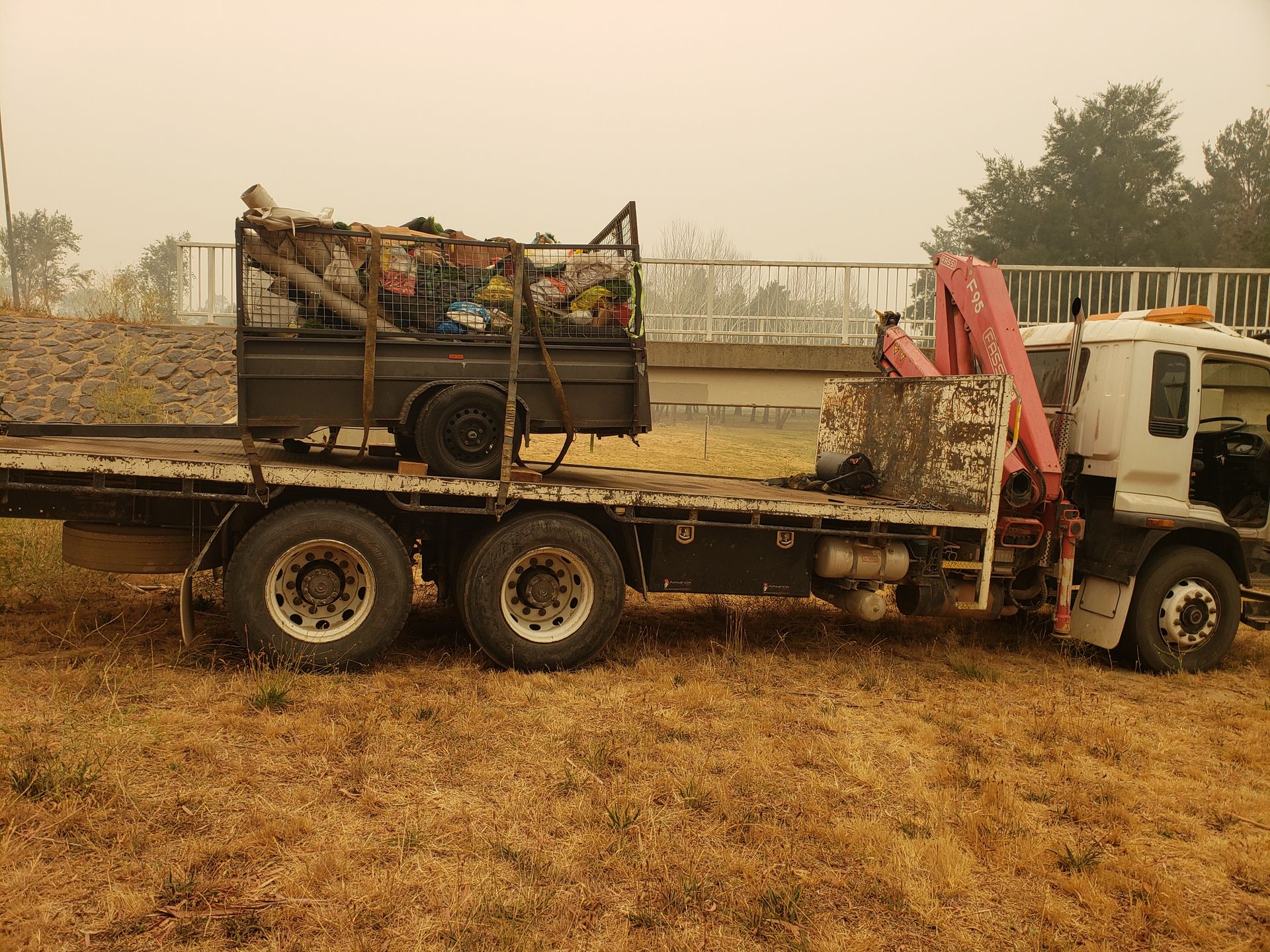 A Flatbed Truck With a Crane on the Back is Parked in a Field — Alexander Crane Tippers in Latham, ACT