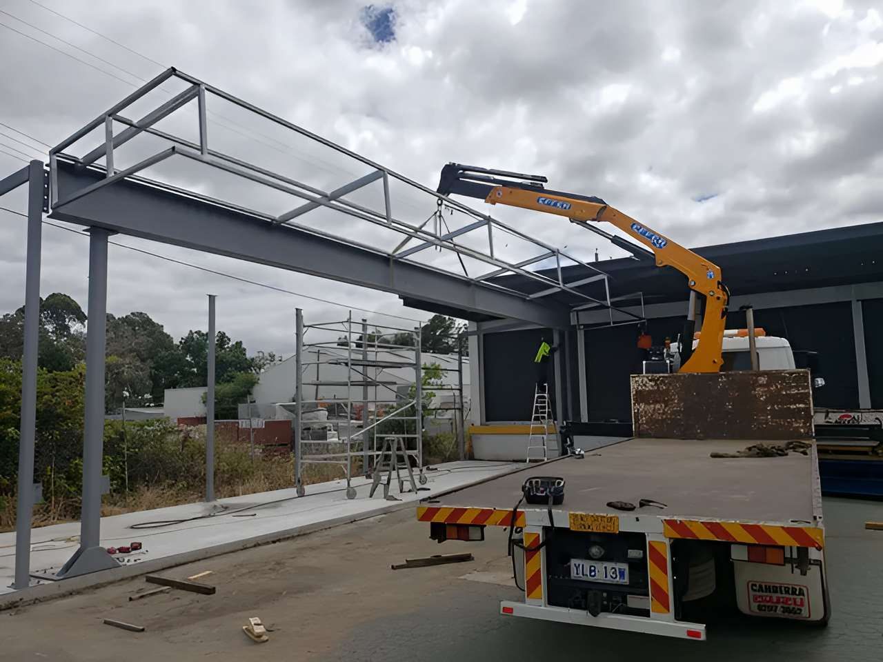 A Truck With a Crane on the Back is Carrying a Metal Structure — Alexander Crane Tippers in Latham, ACT