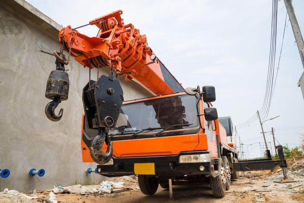 An Orange Crane is Parked in Front of a Building Under Construction — Alexander Crane Tippers in Bungendore, NSW
