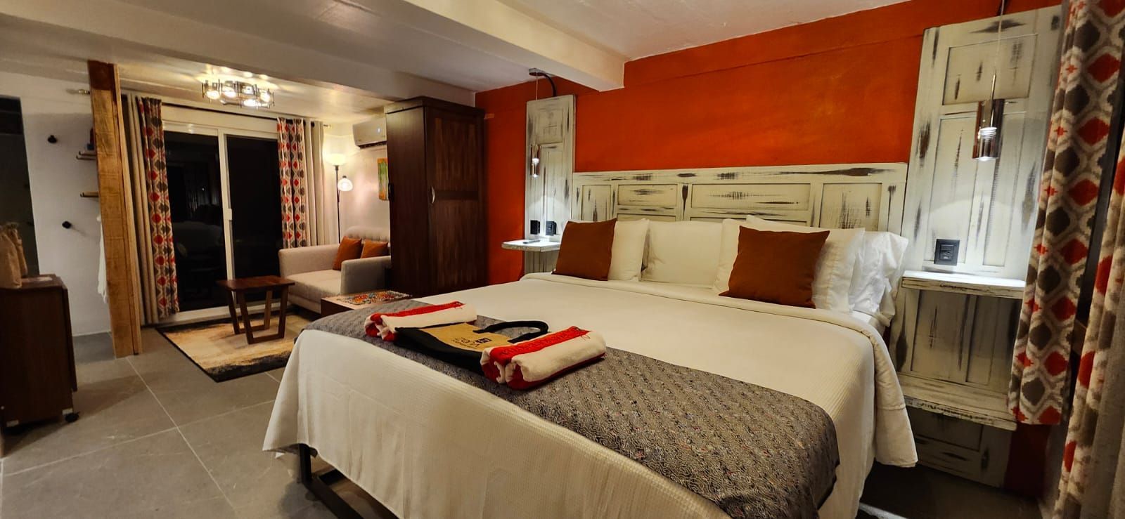 Bedroom with orange wall, large bed, and a sitting area.