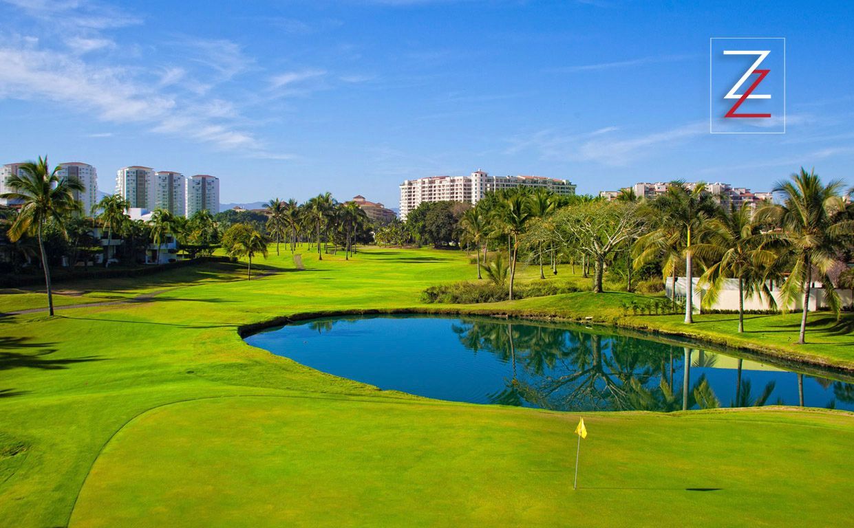 A golf course with a pond in the middle of it.