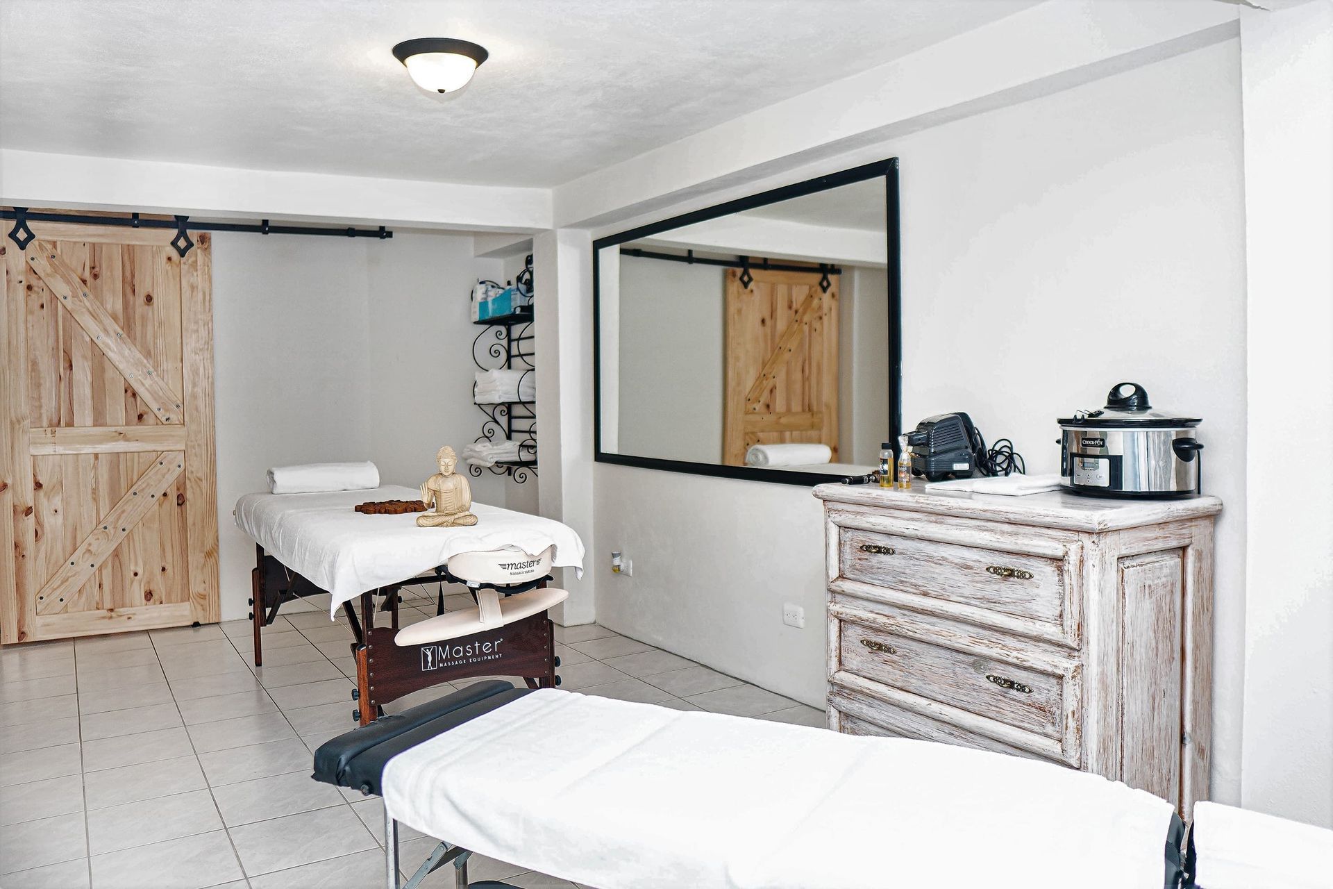 A room with two massage tables , a dresser and a mirror.