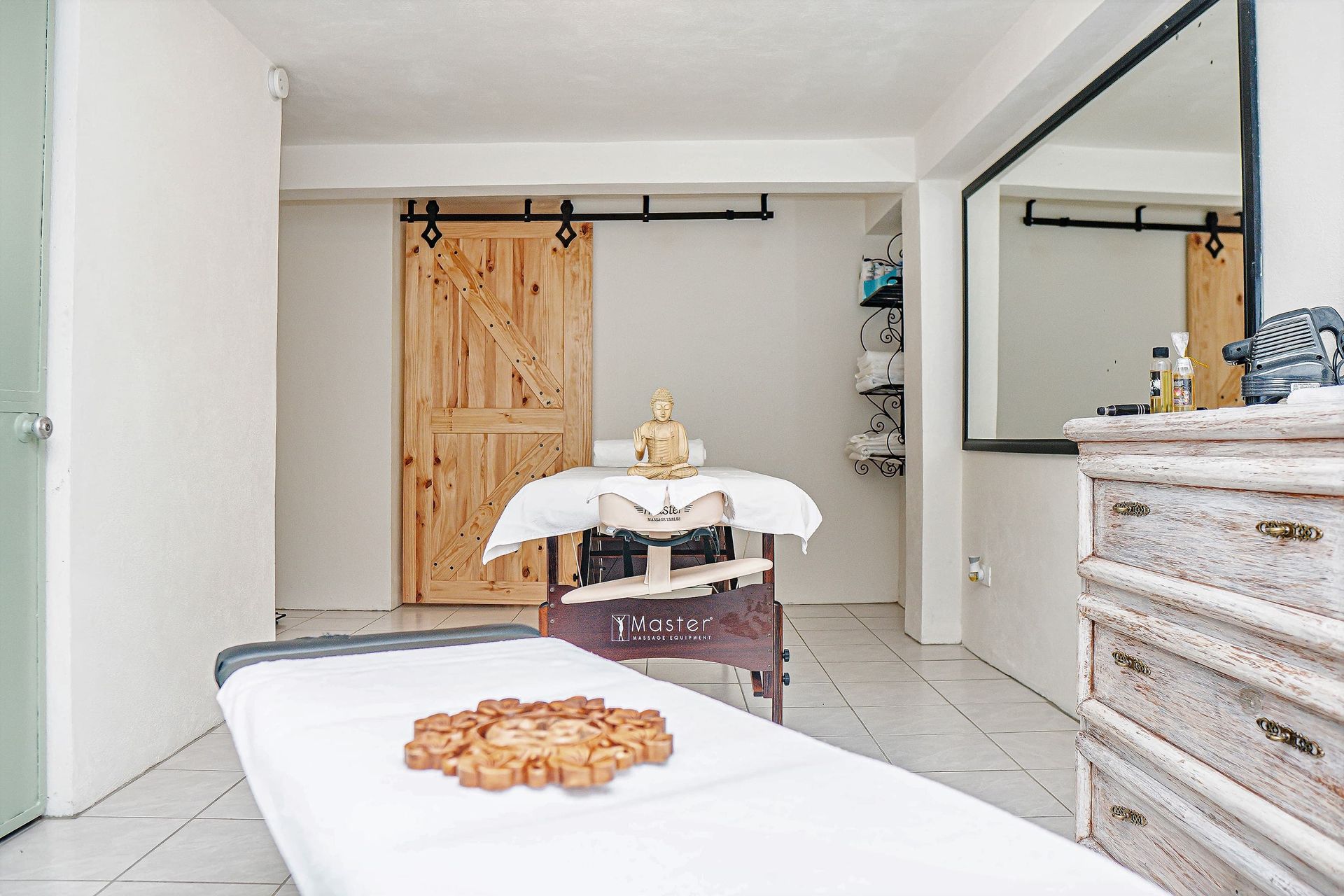 A massage table in a room with a dresser and a mirror.