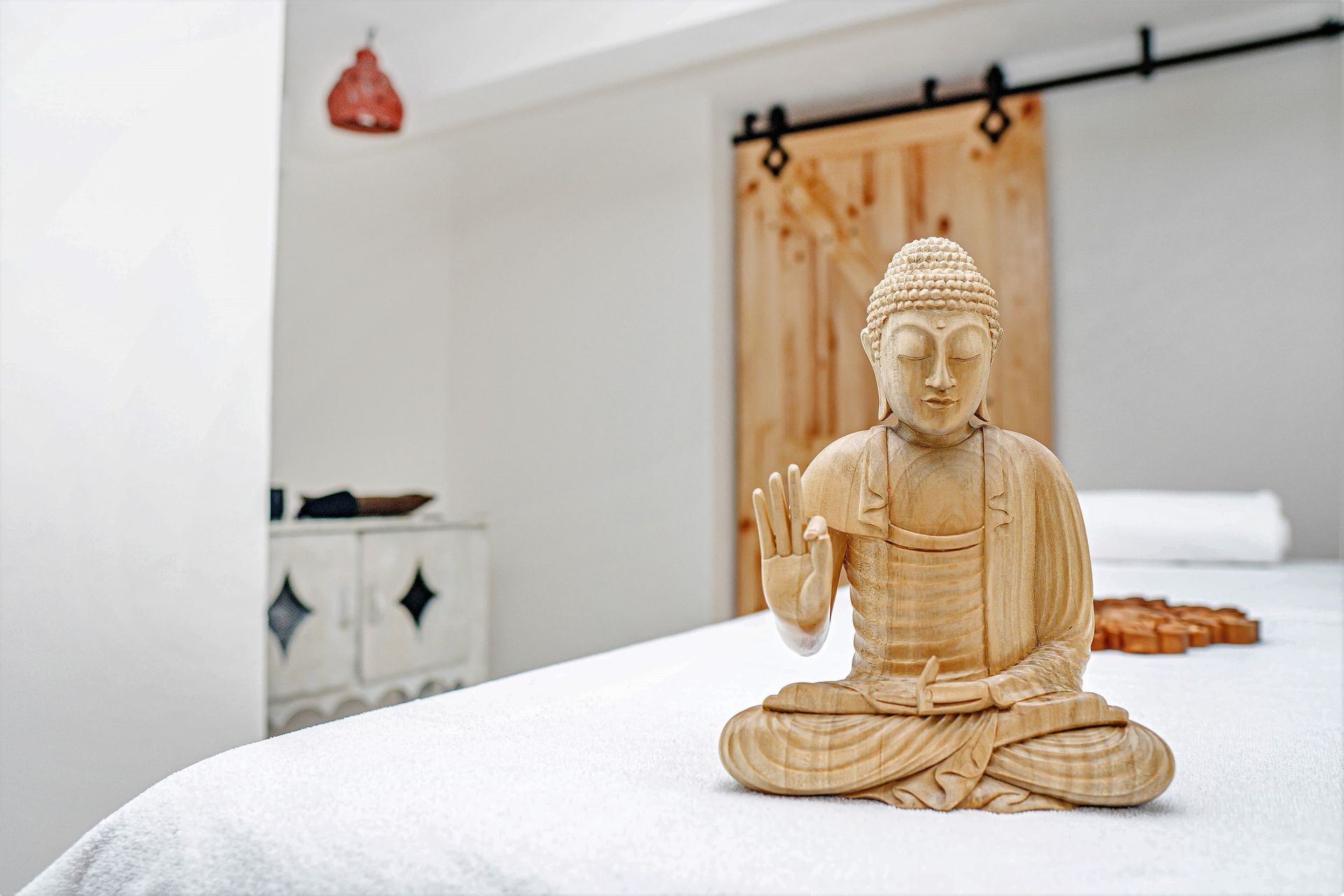 Wooden Buddha statue on a white massage table; spa setting.