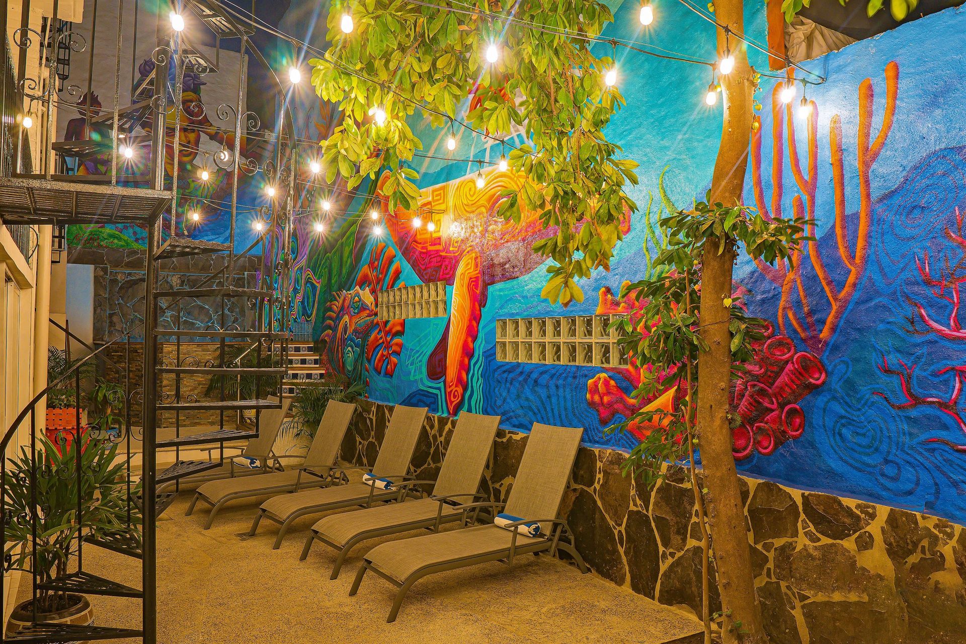 A patio with chairs and a painting on the wall.