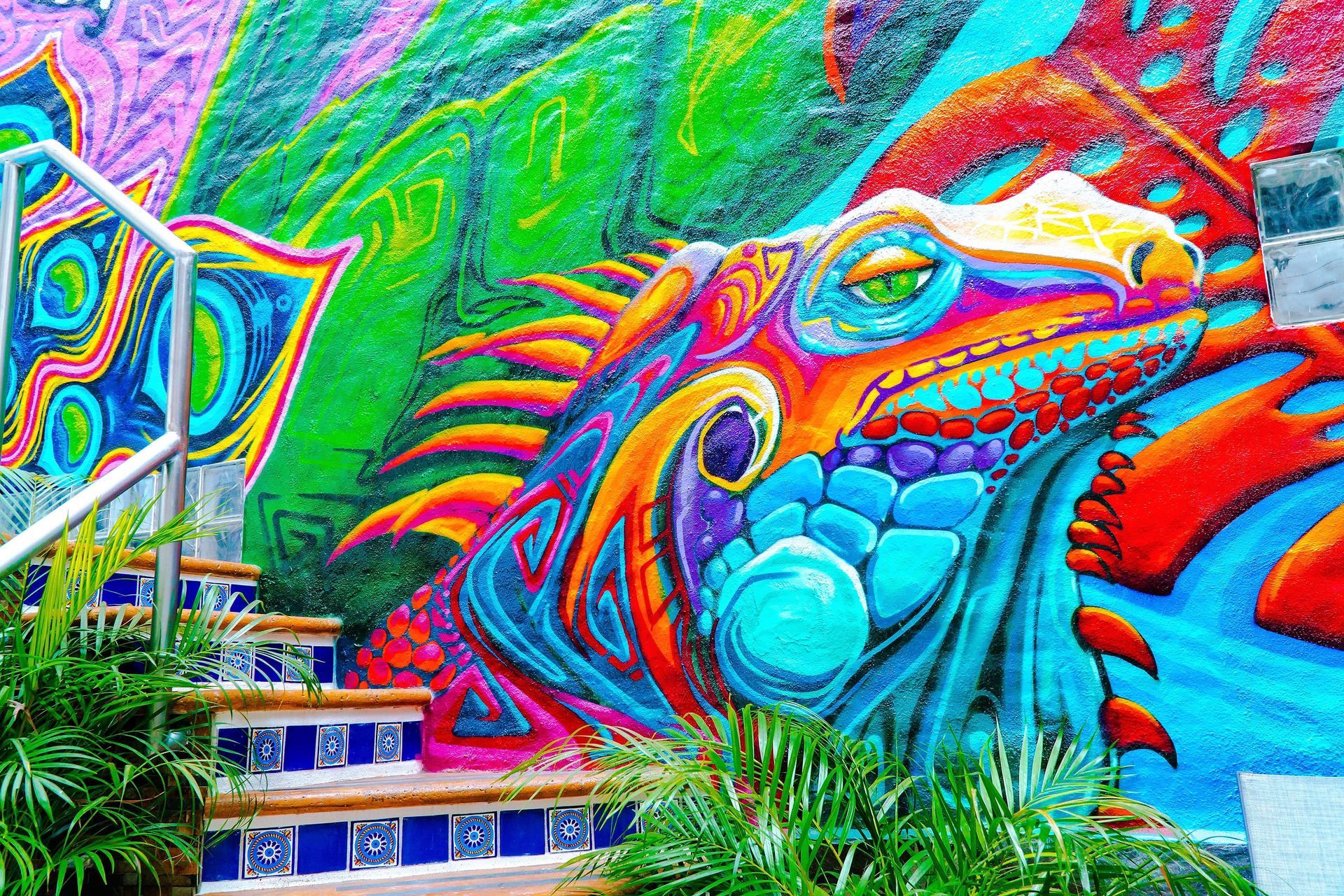 A colorful mural of a lizard on a wall next to stairs.