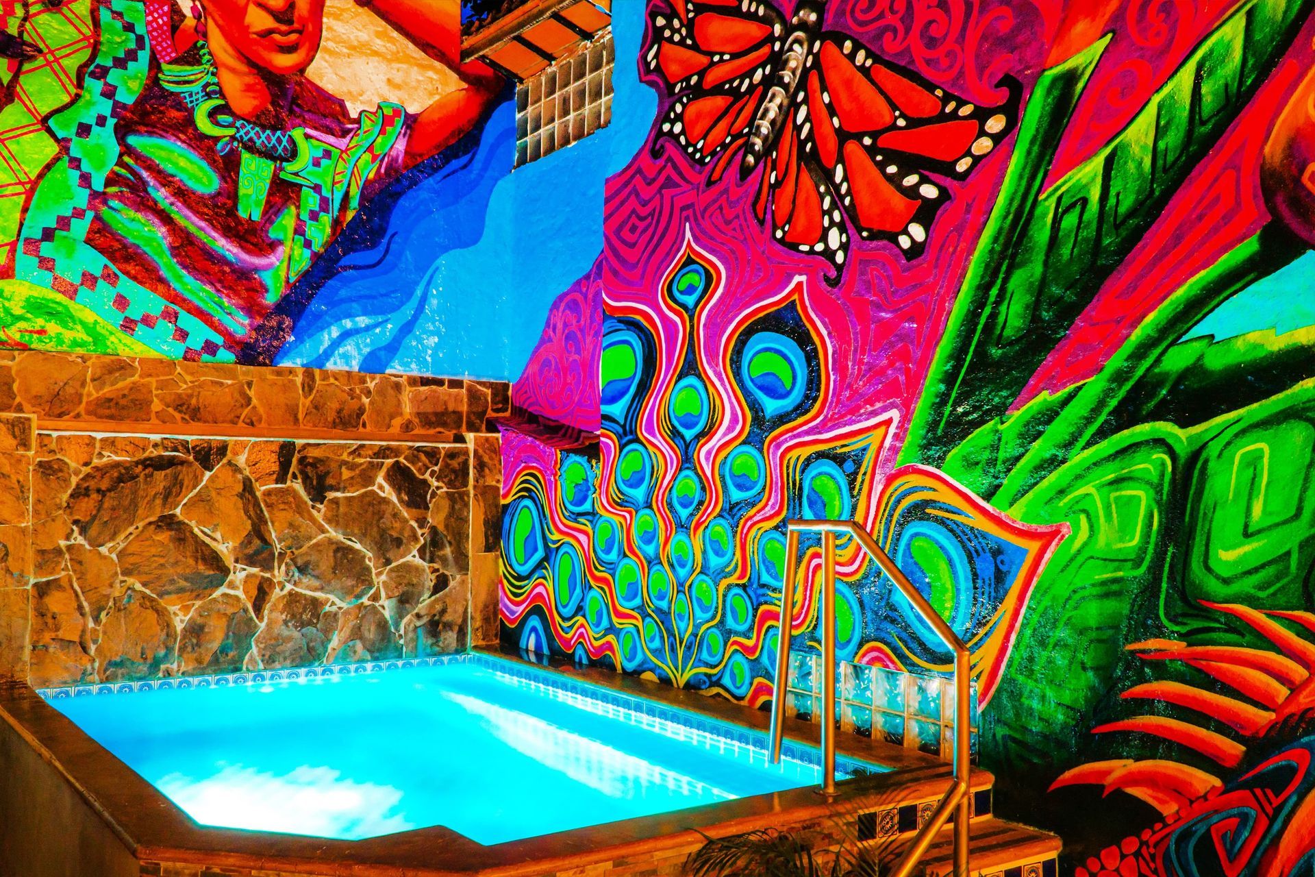 A swimming pool with a colorful mural on the wall behind it.