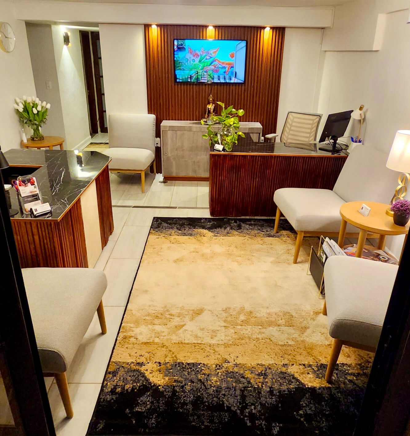 An office reception area with chairs, desks, and a rug. Warm tones and wood paneling create a welcoming space.