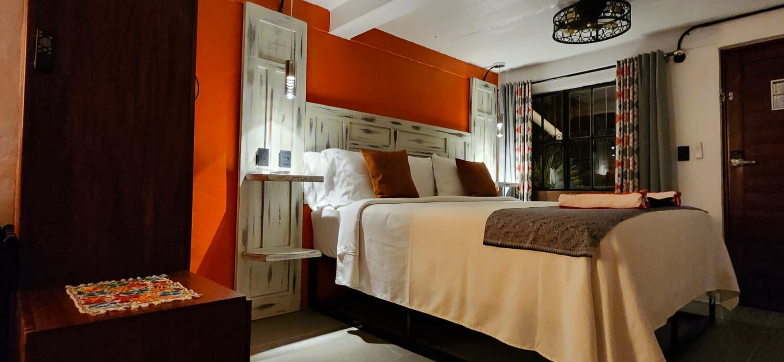 Bedroom with orange walls, a bed, nightstand, and a door.