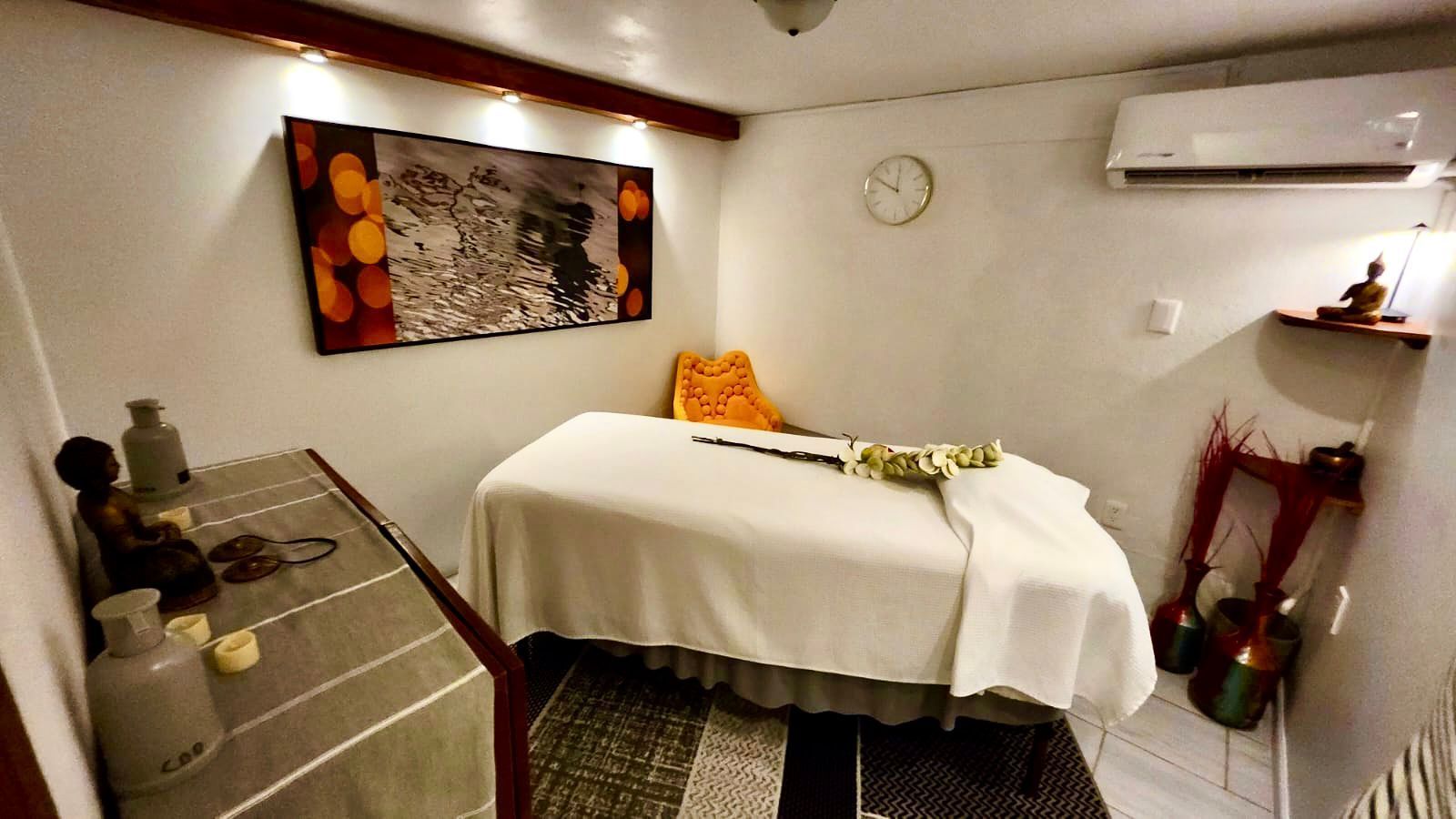 Massage room with massage table, artwork, and decorations.