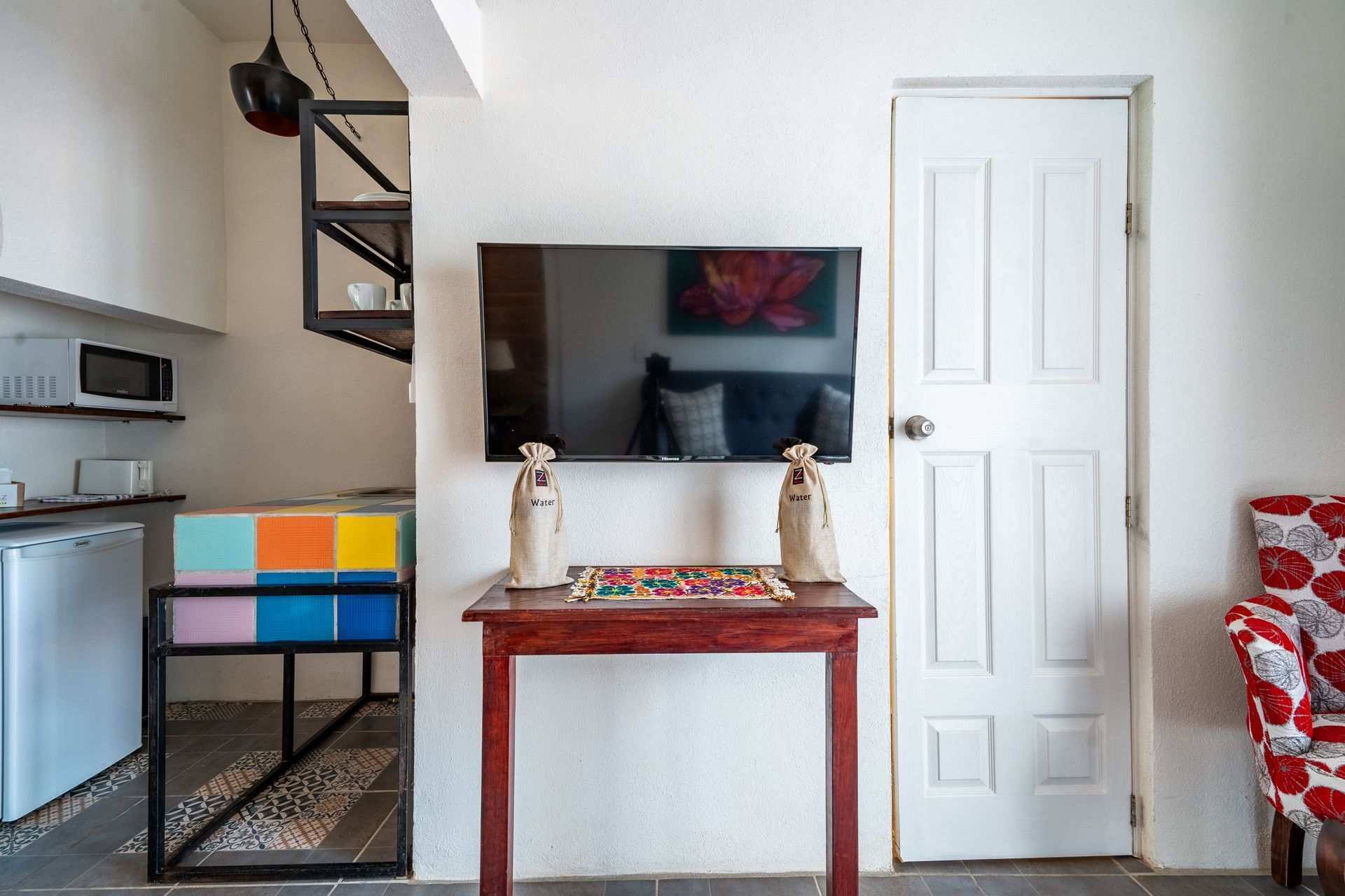 Small living space with TV, kitchen, and a red armchair.