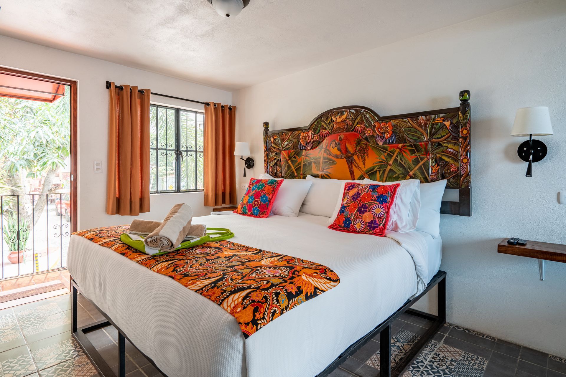 Bedroom with king-sized bed, balcony, vibrant textiles, and colorful headboard.