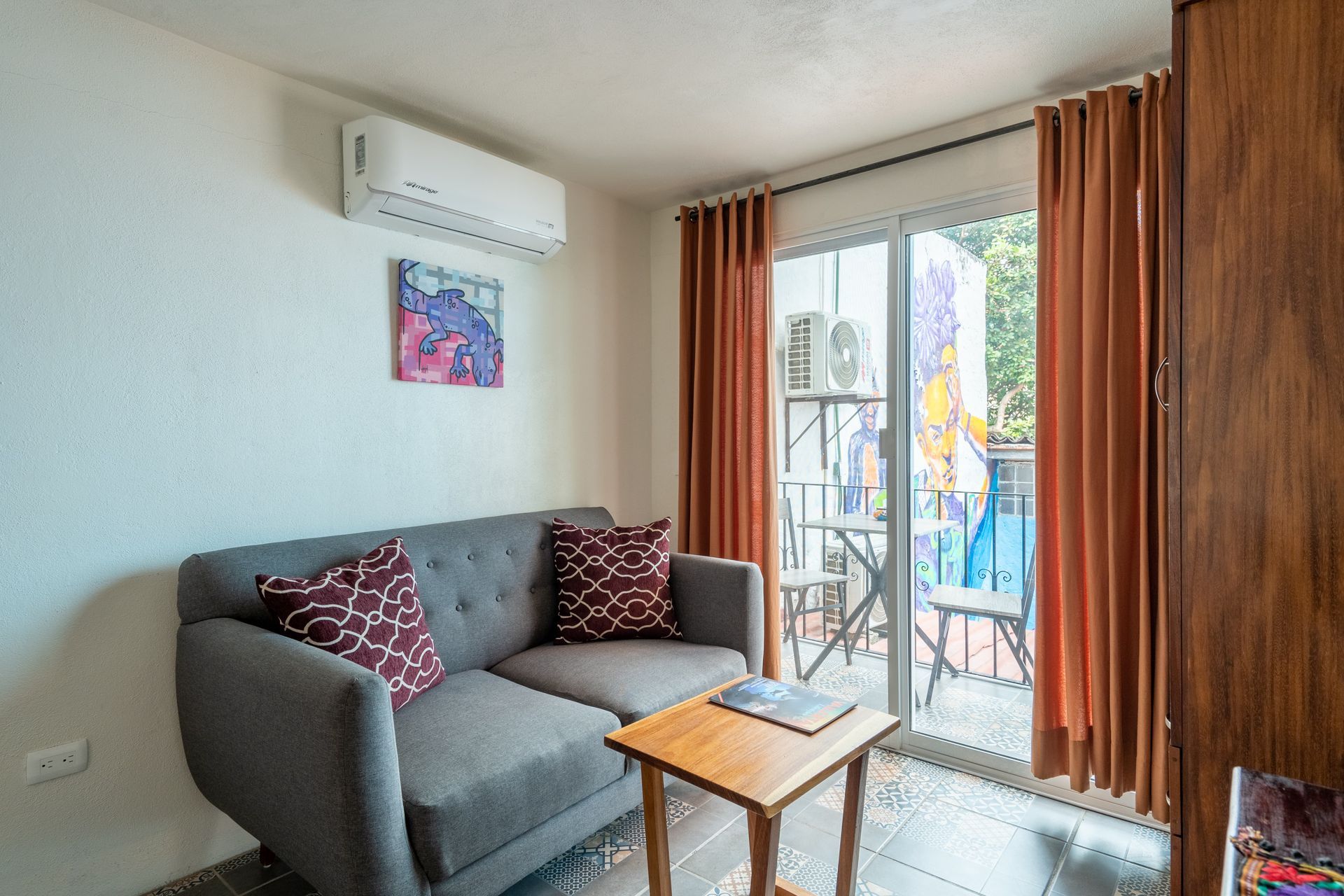 Cozy living space with a gray sofa, small wooden table, and balcony access.