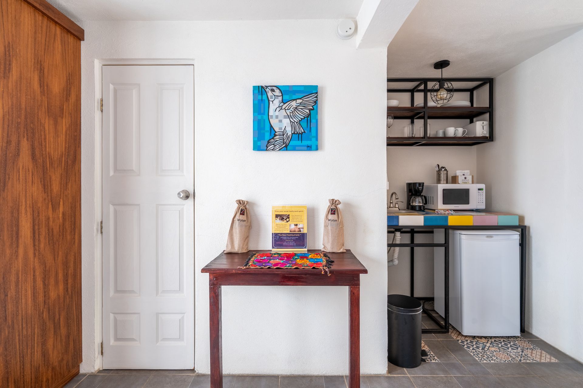 Small studio apartment with kitchenette, artwork, and wooden table.