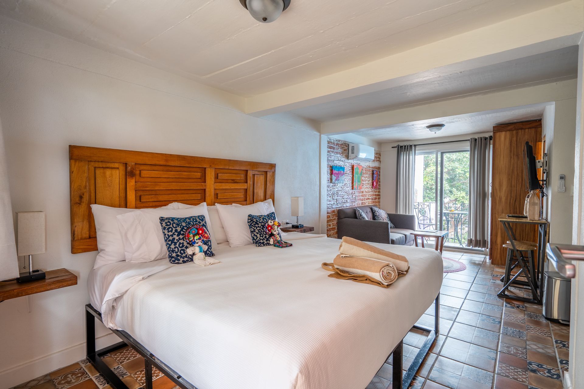 Bedroom with a king-sized bed, wooden headboard, and balcony access; brick flooring.