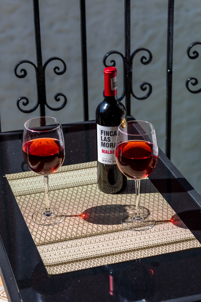 A bottle of pinot noir sits on a table next to two glasses of wine