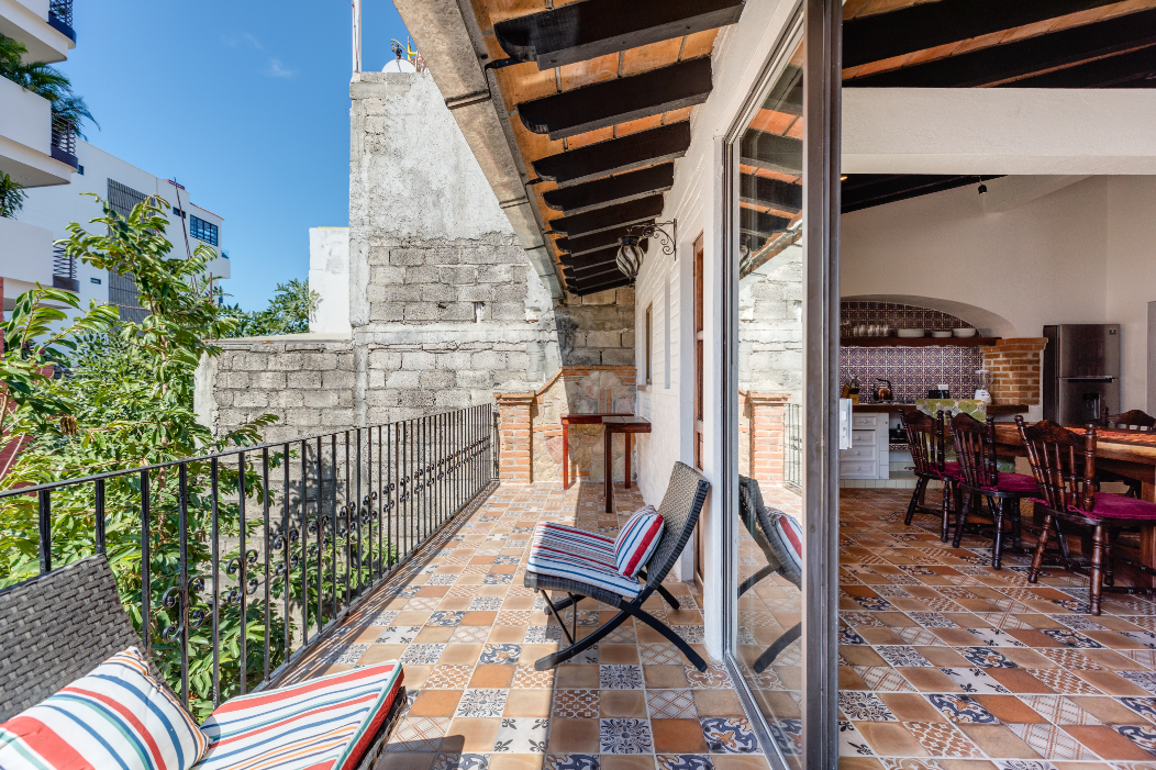 A balcony with chairs and a table in a house with a sliding glass door.