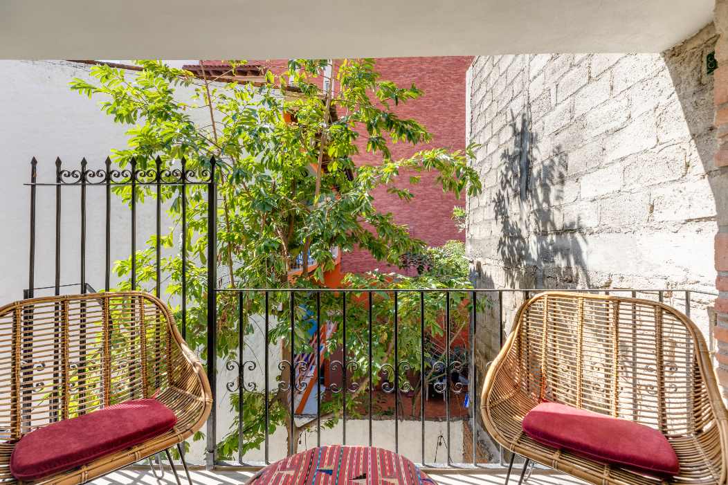 Two wicker chairs are sitting on a balcony overlooking a tree.