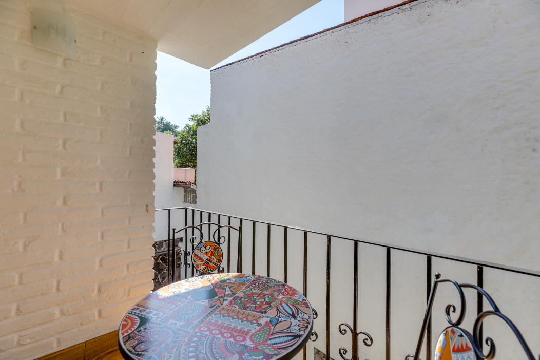 A balcony with a table and chairs and a white brick wall.