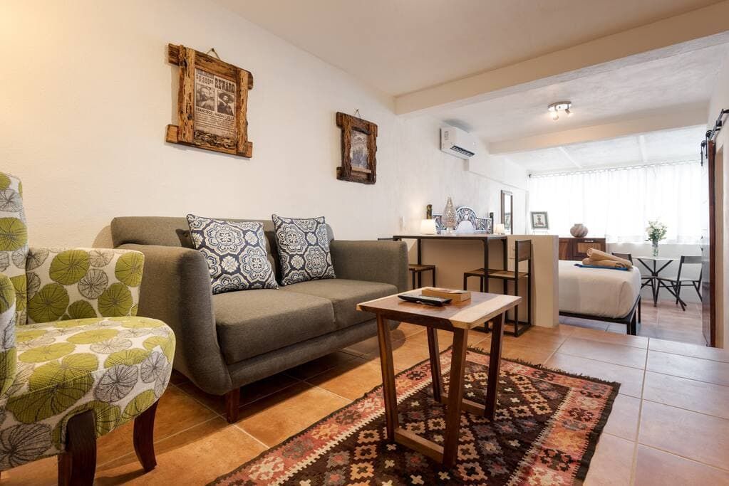 A living room with a couch , chair , coffee table and rug.