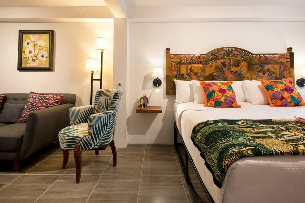 A hotel room with a king size bed , chairs , and a couch.