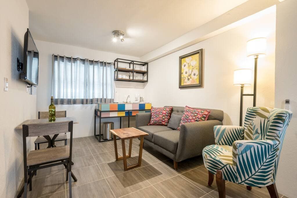 A living room with a couch , chairs , table and television.
