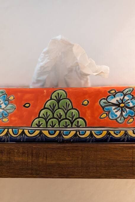 A tissue box with a floral design on it is sitting on a wooden table.