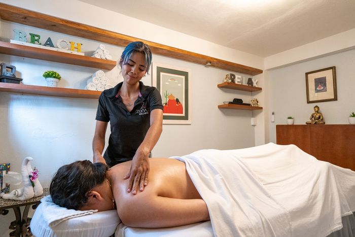 Massage therapist giving a back massage in a spa-like setting.