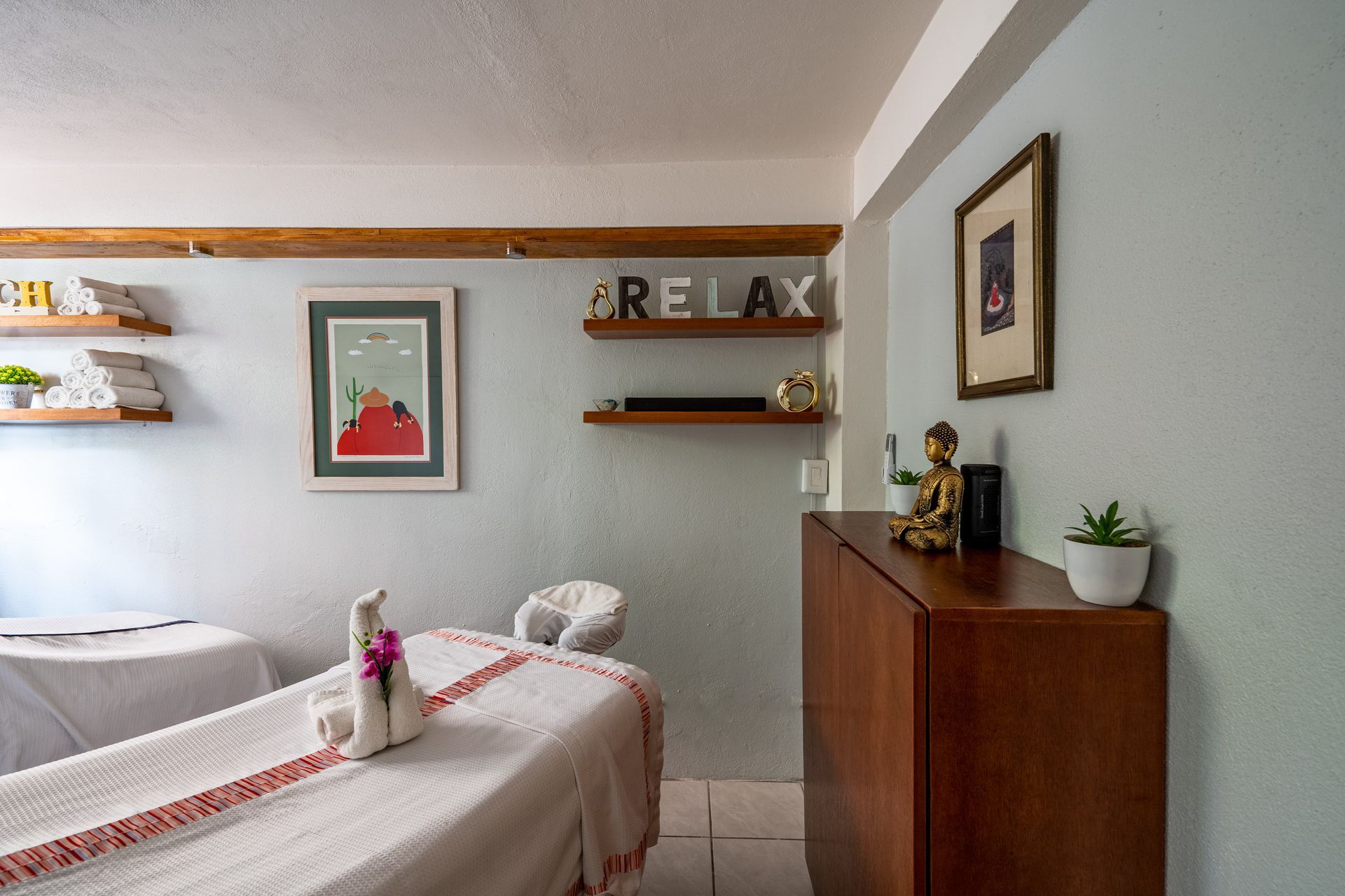 A room with two massage tables and a shelf with the word relax on it.