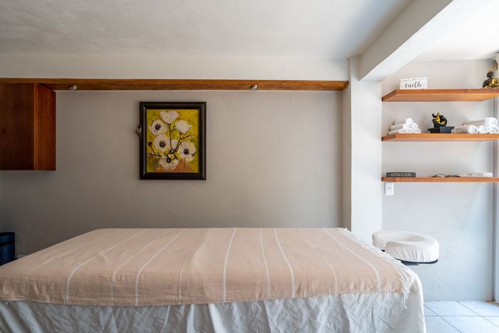 Massage table in a room with shelves and a floral painting.