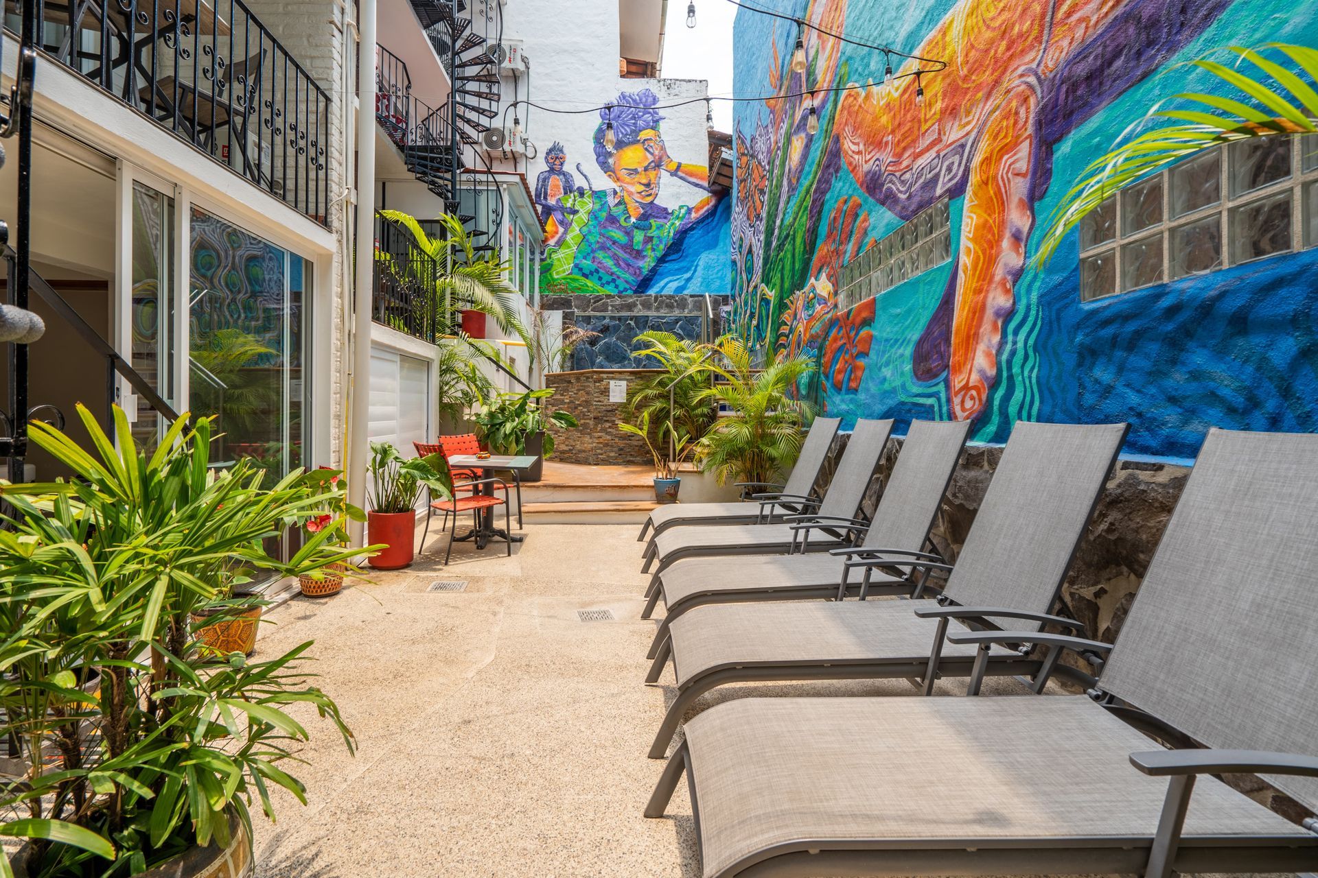 A row of lounge chairs in front of a building with a mural on the wall.