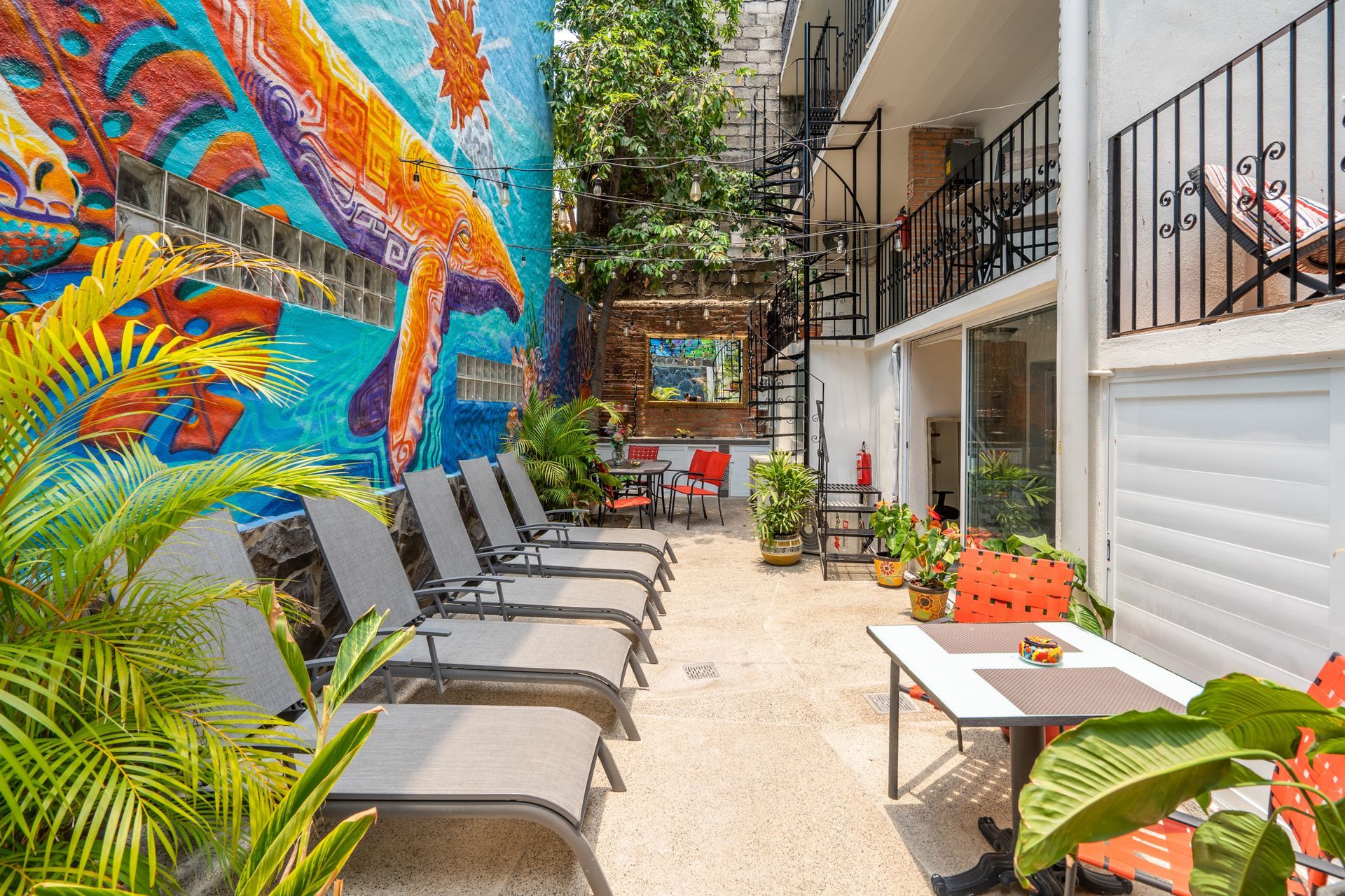 A patio with a table and chairs in front of a building with a mural on the wall.