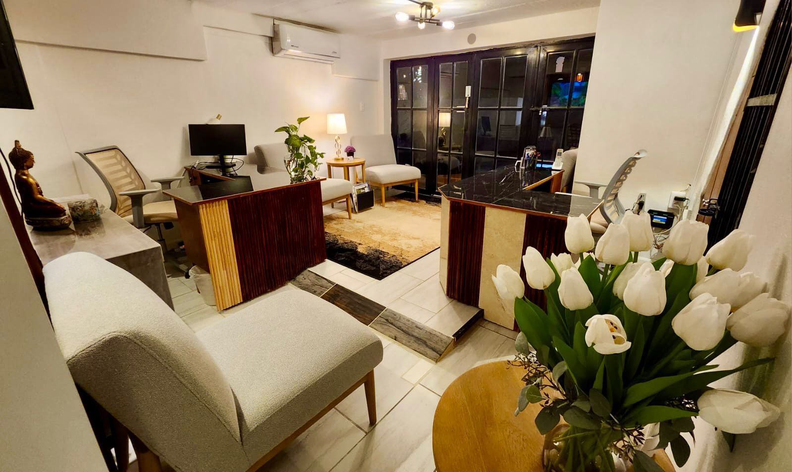 Cozy living room with white tulips, beige furniture, and dark wood accents.